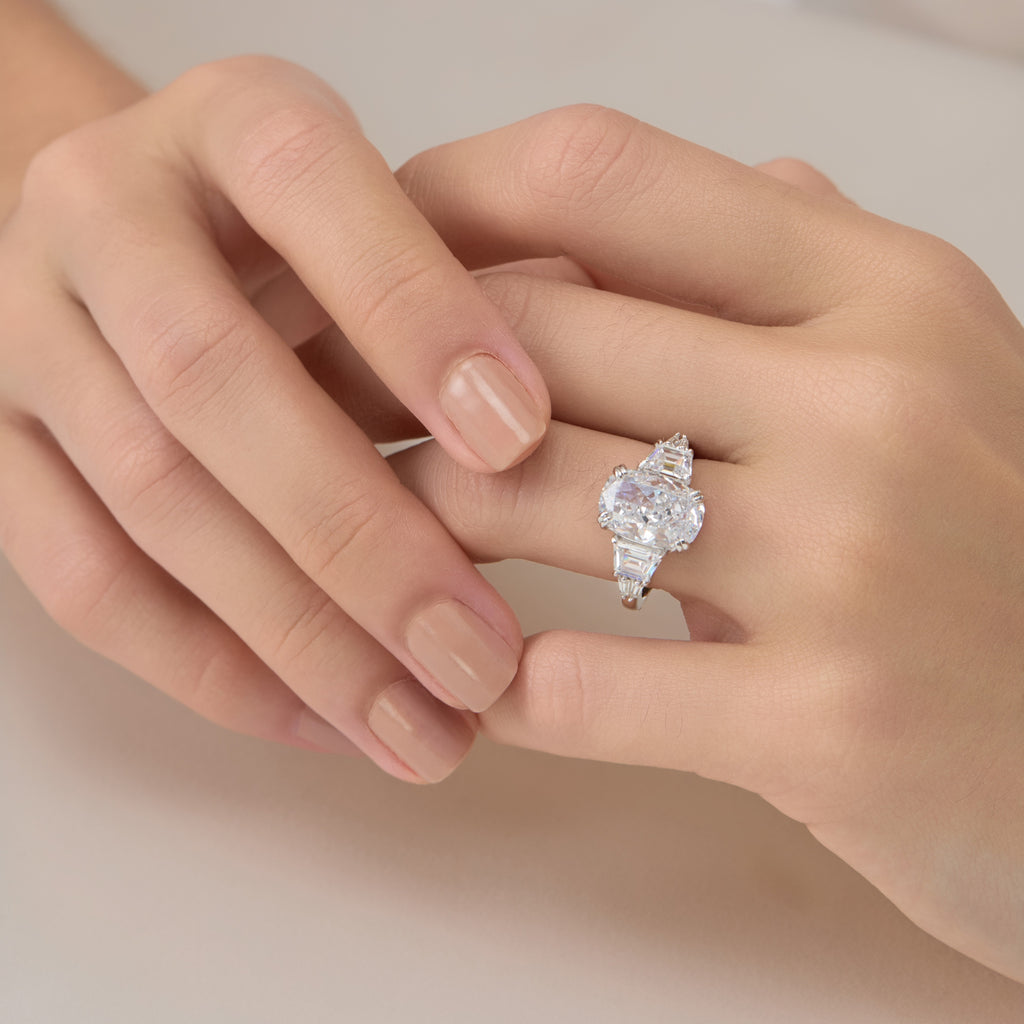 Elegant front view of 3.5 Carat Oval Multi-Stone Engagement Ring on finger with hand gently touching the other hand.