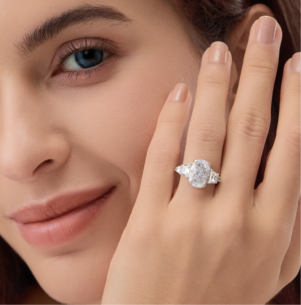 Woman wearing 3.5 Carat Oval Multi-Stone Engagement Ring, close-up near face.