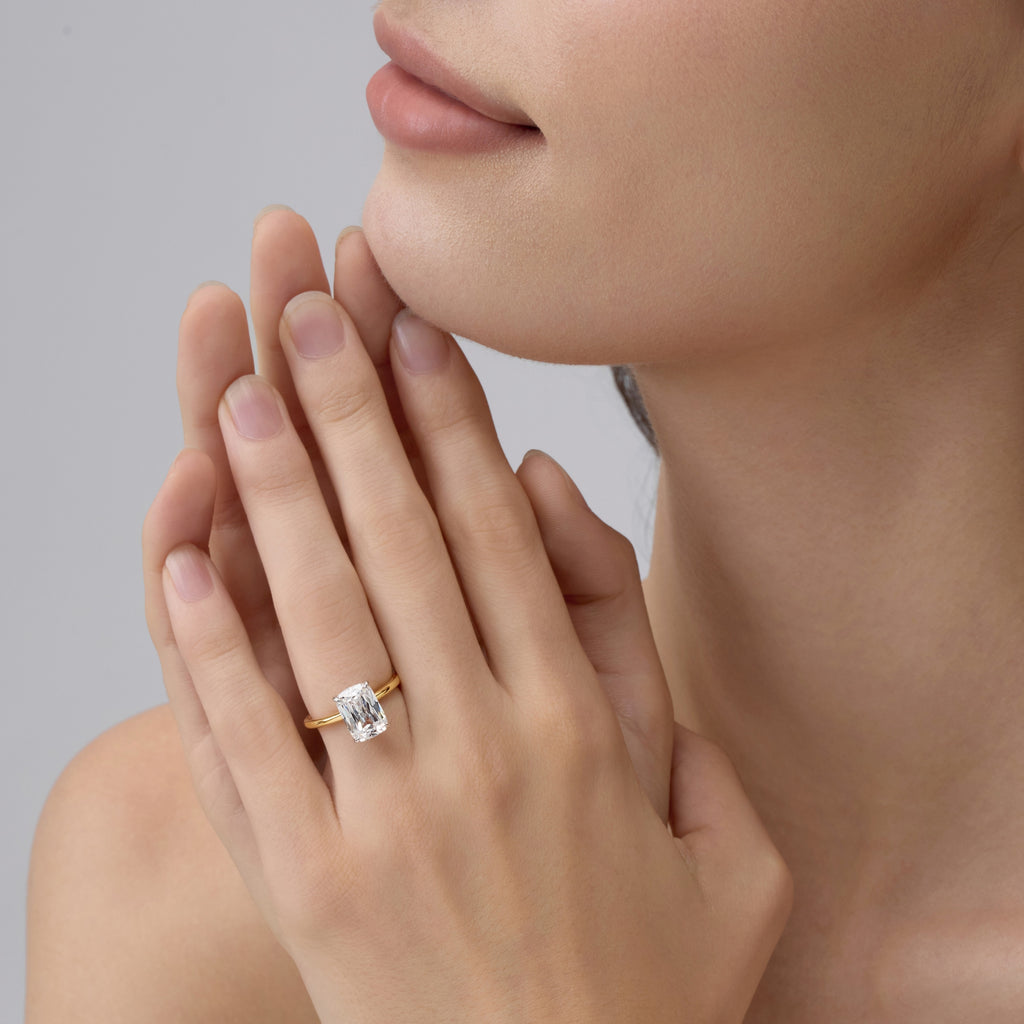 Close-up of a hand wearing Club Lux 3 Carat Elongated Cushion Ring on a neutral background, old mine cut sparkle