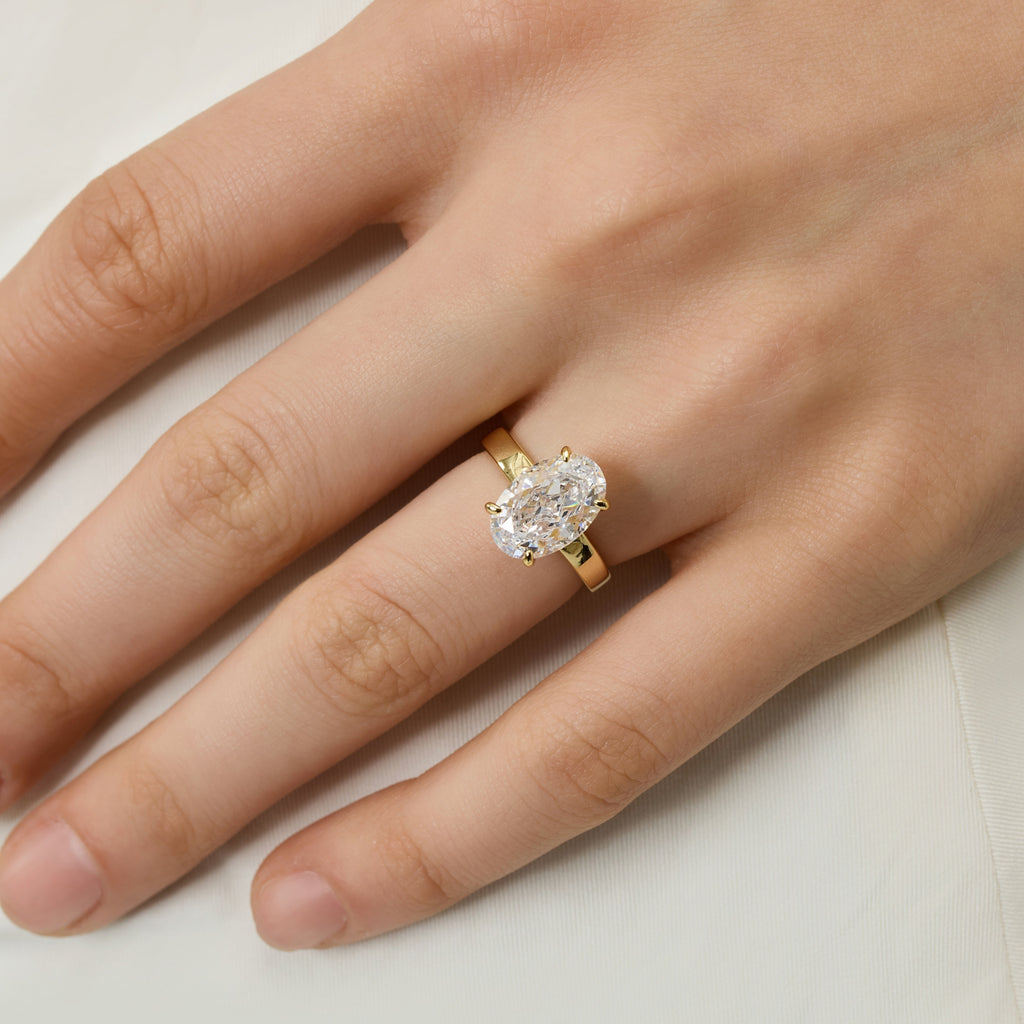 Front view close-up of 3.5 Carat Oval Solitaire Engagement Ring on finger, highlighting modern flat-edge band | Club Lux