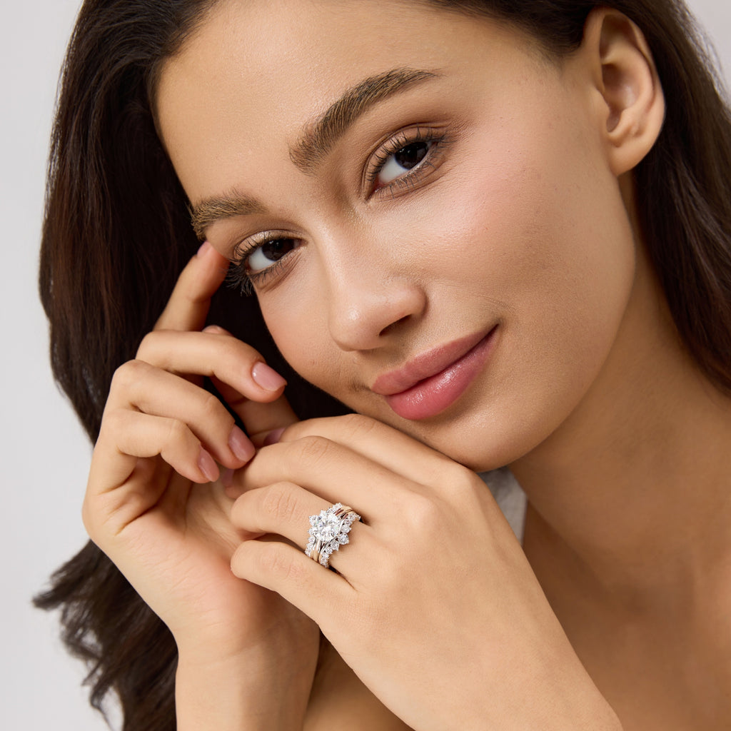 Woman smiling while wearing 3 carat round moissanite engagement ring bridal set, close-up hand view.