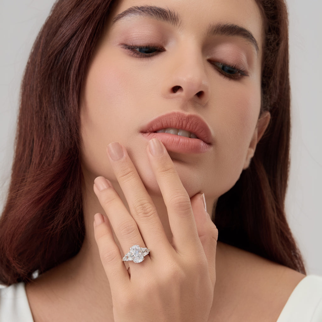 Woman touching chin while wearing 3.5 Carat Oval Multi-Stone Engagement Ring.