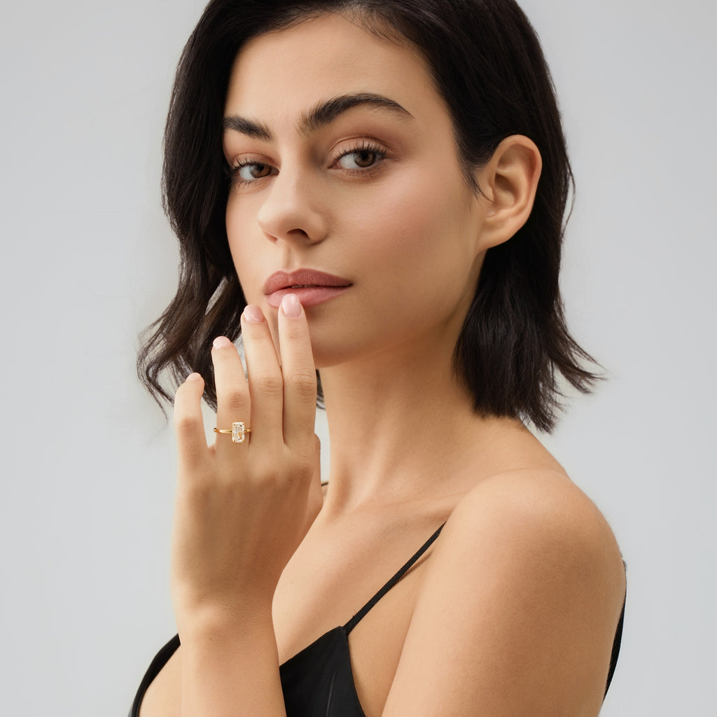 Woman wearing a ring on her finger against a plain background