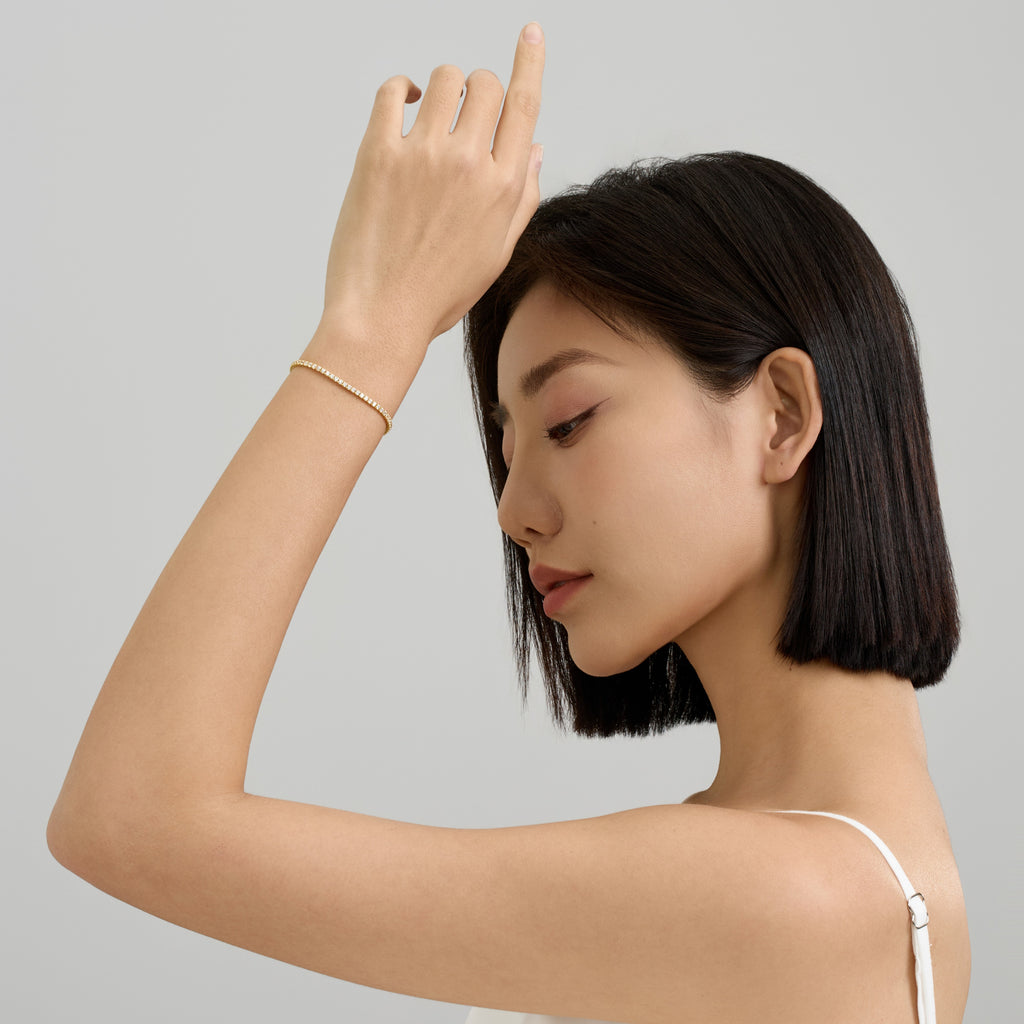 woman Lifting Arm Gracefully Wearing 2mm Round Brilliant Tennis Bracelet in 18k Gold-Plated Sterling Silver