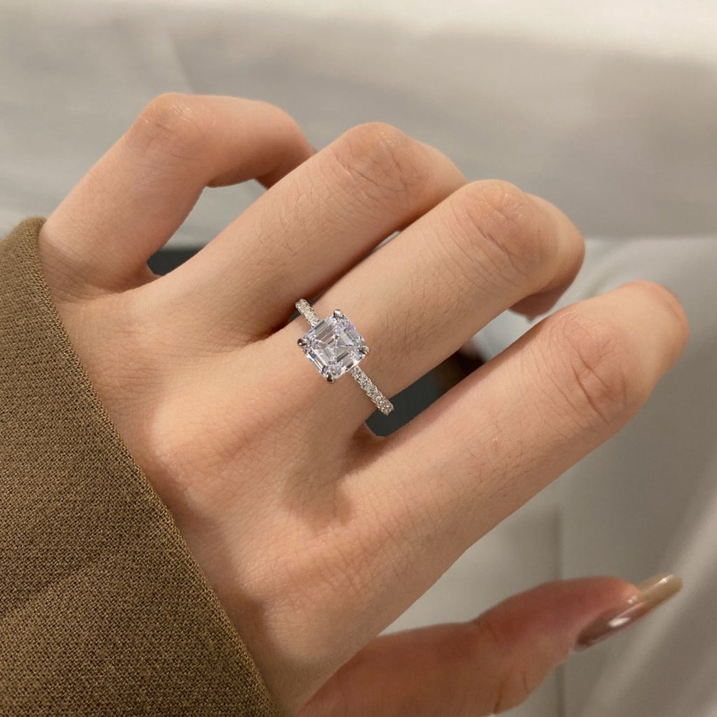 Crafted with classic step-cut, an angular square shape, and polished clipped edges, this stunning 2.0 carat cubic zirconia sparkles brilliantly at the heart of a sophisticated pave band, with a hidden halo of dazzling pave stones that will leave you radiant from every angle!