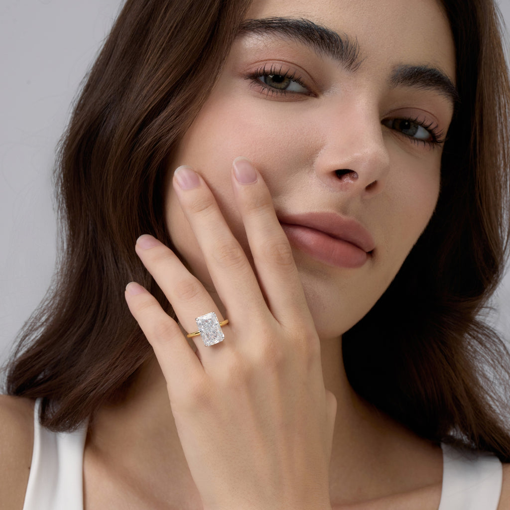 Woman wearing Club Lux Radiant Cut Two Tone Engagement Ring and gently touching her face – 18K Gold and Rhodium Plated over Sterling Silver