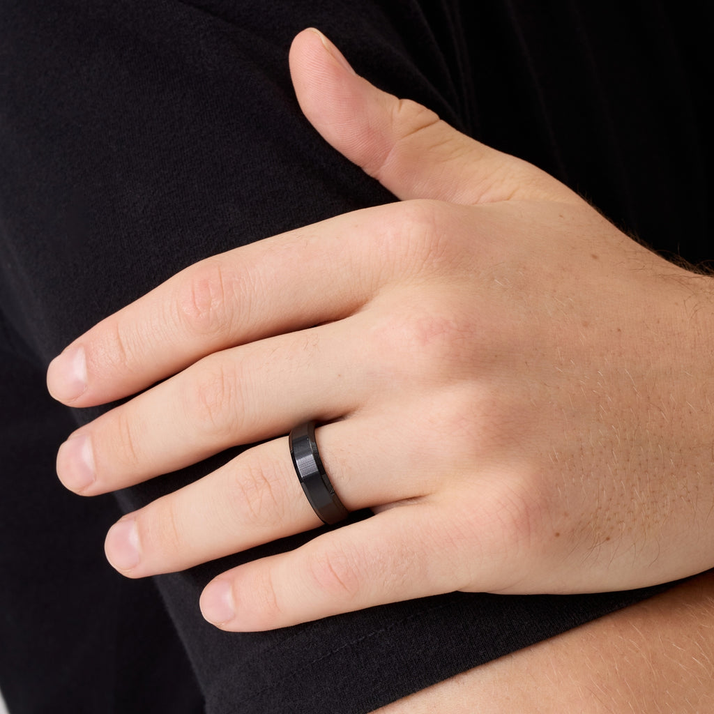 Close-up of man’s hand wearing black titanium wedding band while touching his arm