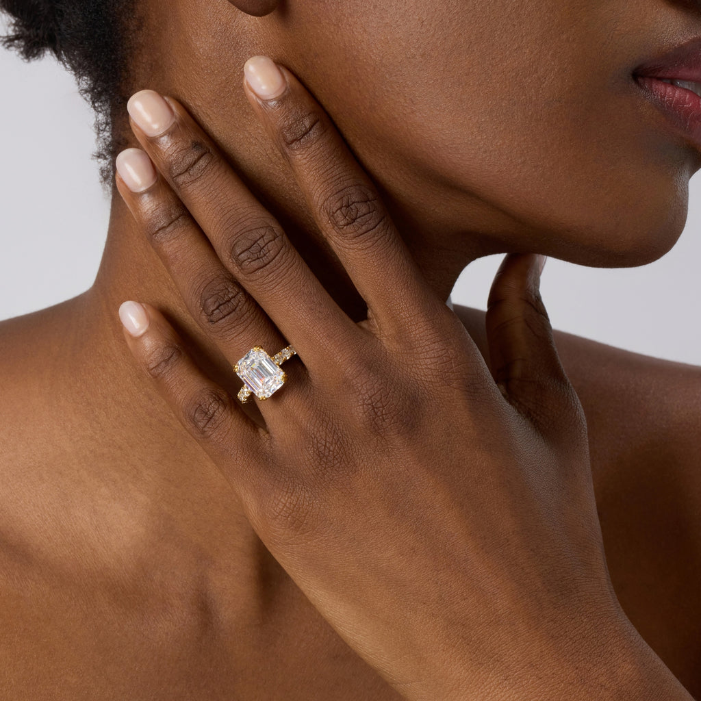 Club Lux 5ct emerald cut engagement ring on a lady's hand, front view, hidden halo, double prong, gold band