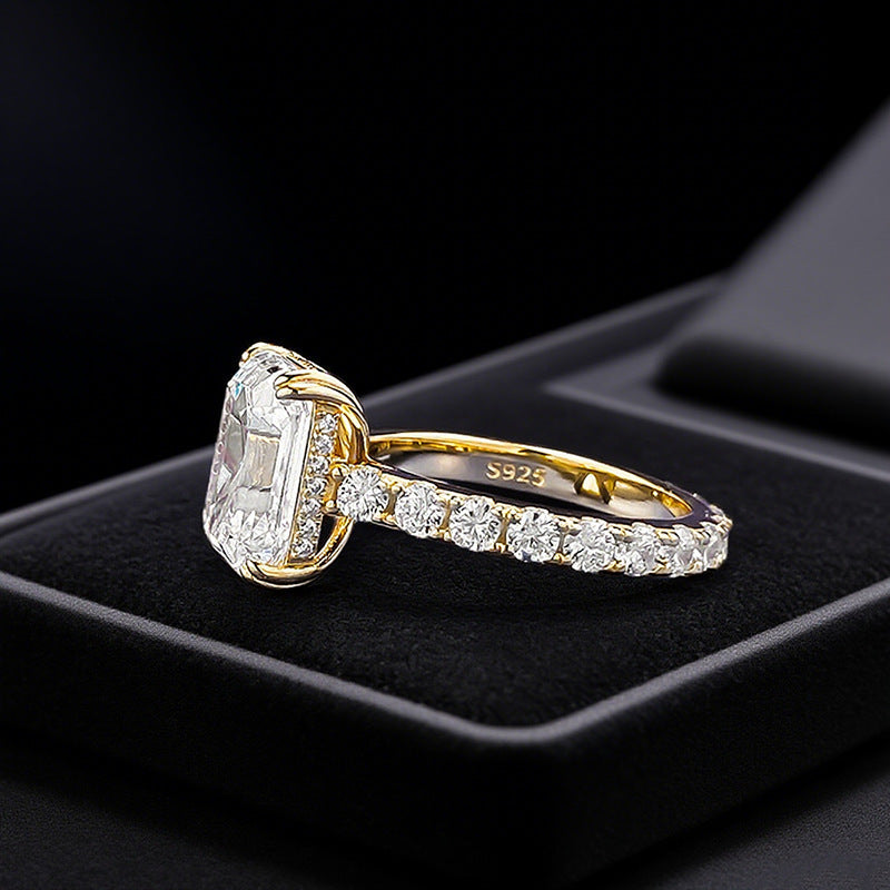 Club Lux 5ct emerald cut engagement ring side view on ring box, cathedral setting, hidden halo, gold eternity band