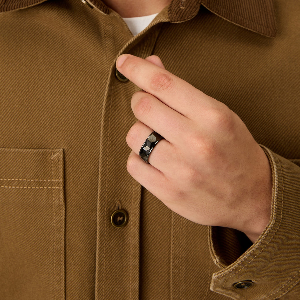 Lifestyle photo of Club Lux Men’s Black Tungsten 8mm Faceted Wedding Band worn while buttoning brown jacket.