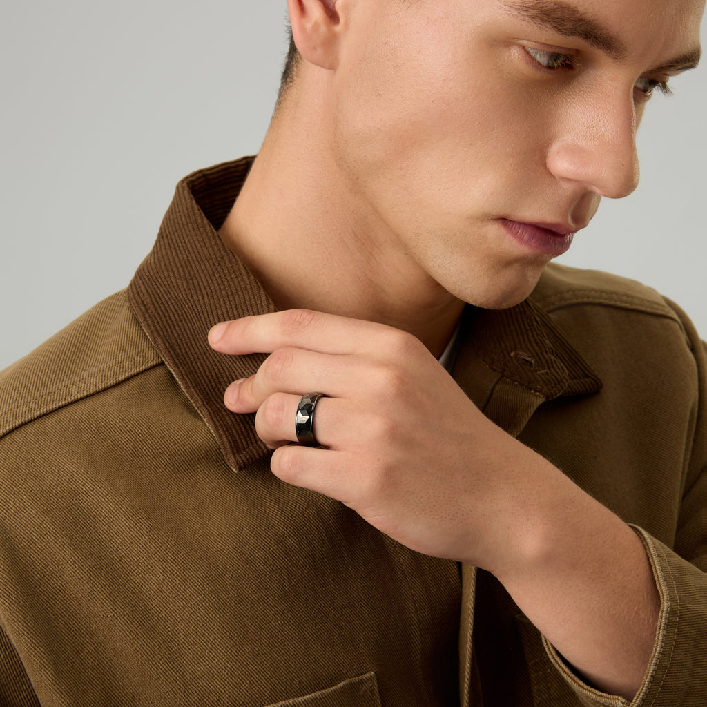 Men’s Black Tungsten Carbide Ring by Club Lux, 8mm faceted design, shown while touching shoulder with edge detail visible.