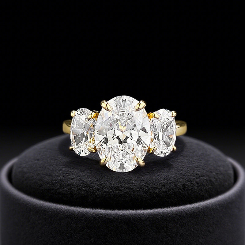Close-up front view of gold oval trilogy engagement ring with 4ct TW stones.