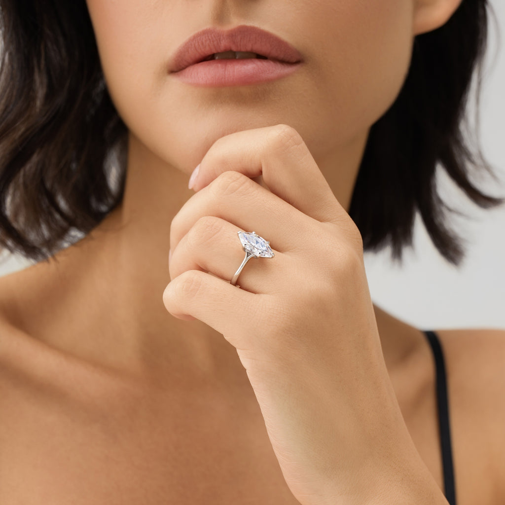 Close-up of woman wearing marquise solitaire ring, side view showing split shank setting and refined craftsmanship.