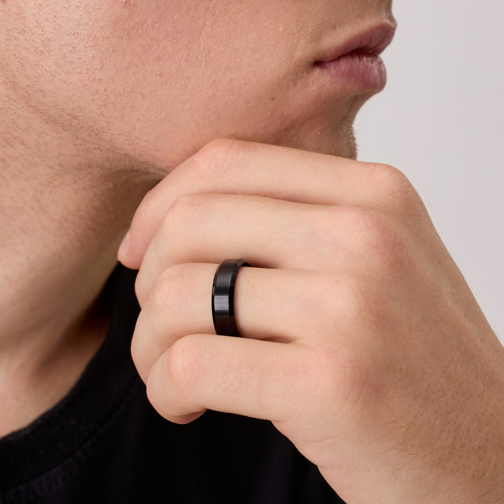 Close-up of man wearing black titanium wedding band while touching his chin