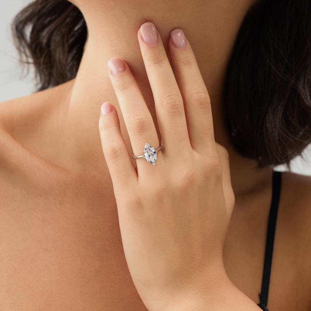 Elegant woman wearing marquise engagement ring, gently touching her neck – showcasing the elongated shape and refined brilliance.