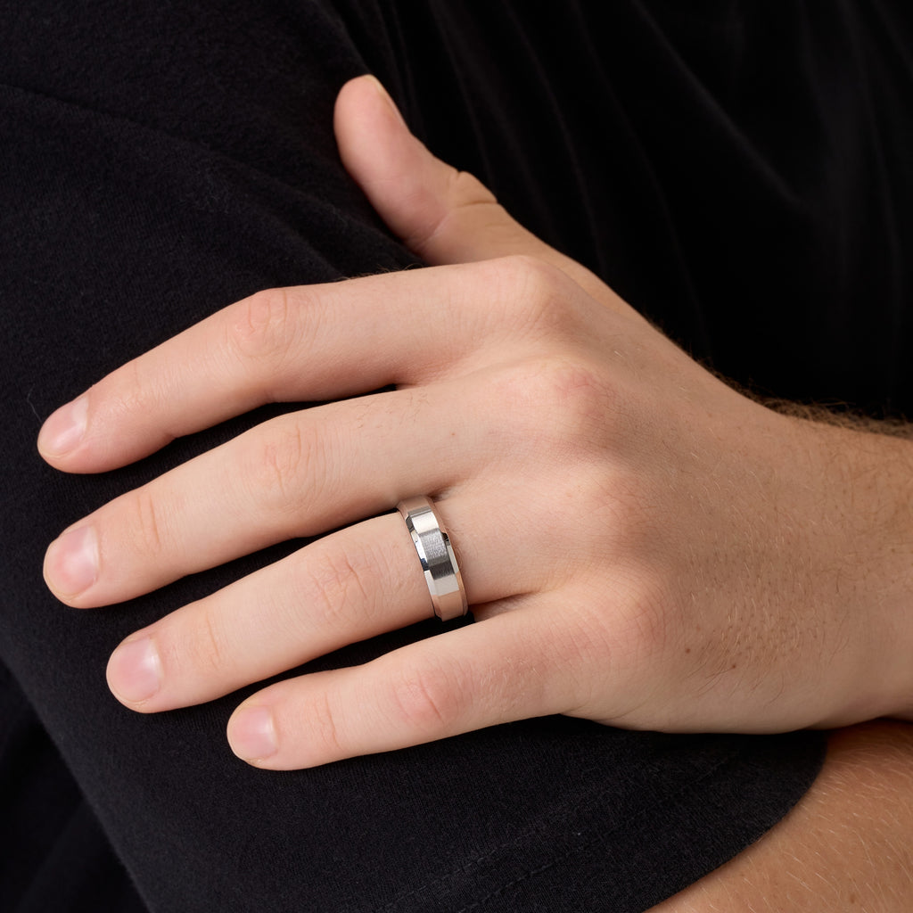 Close-up of men’s silver titanium wedding band on hand while touching his arm