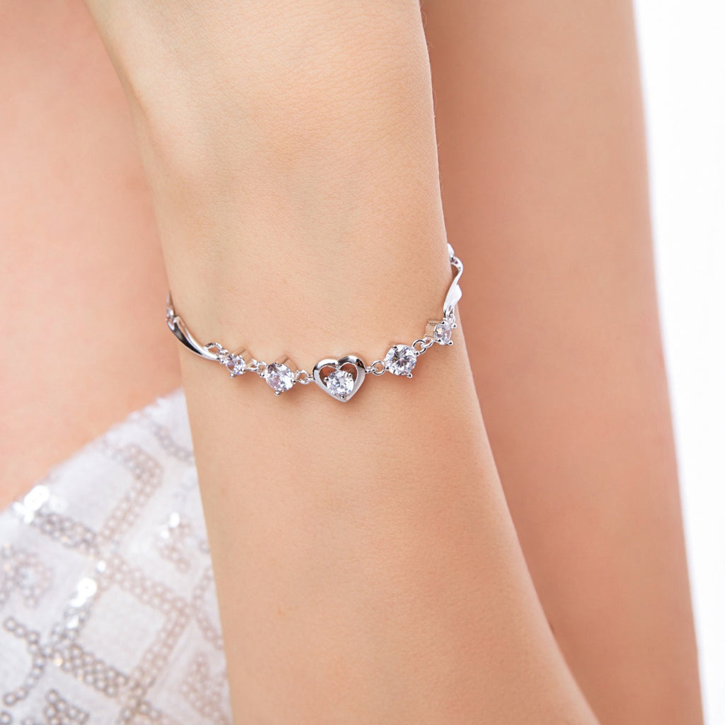This one-of-a kind heart bracelet will have your heart a-flutter!  The unique chain of curves is strung with a bezel-set centre heart cubic zirconia, four graduated round-cut stones that sparkle and shine, plus a tiny bezel crystal. It's ready for loving - someone special, or just yourself!