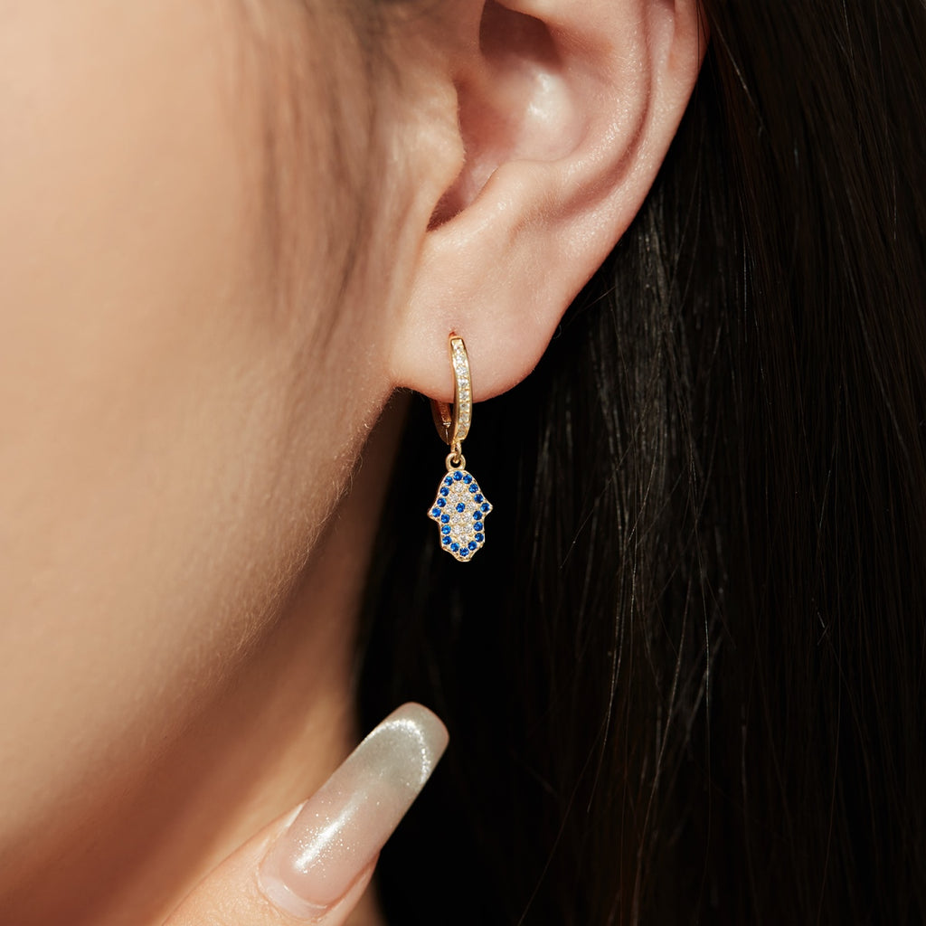 These shimmery sterling silver earrings bedazzled with cubic zirconias bring the timeless power and strength of an ancient Mesopotamian symbol - the hamsa hand - to your ears! Elevate your look with a pair of Gold or Silver Earrings!