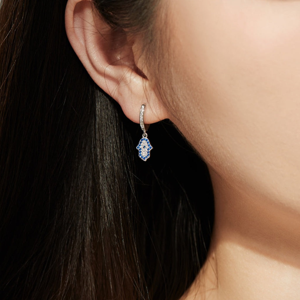 These shimmery sterling silver earrings bedazzled with cubic zirconias bring the timeless power and strength of an ancient Mesopotamian symbol - the hamsa hand - to your ears! Elevate your look with a pair of Silver or Gold Earrings!